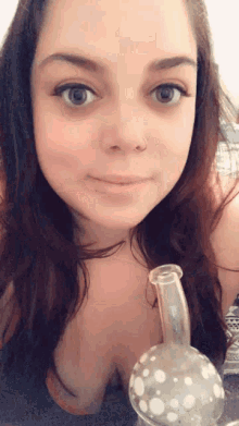 a woman with a nose ring is holding a bong