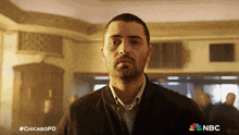 a man with a beard is standing in front of a nbc ad