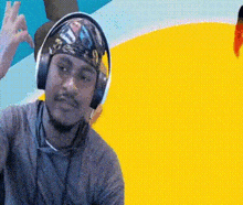 a man wearing headphones and a bandana on his head is giving the ok sign .