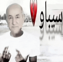 a man in a white shirt stands in front of a wall with arabic writing