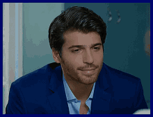 a man wearing a blue suit and a blue shirt is smiling