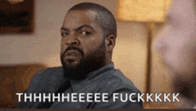 a man with a beard is sitting on a couch and says thhhhheeee fuckkkk .