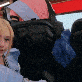 a girl with blonde hair is sitting in a car with a backpack on her back that says ok on it