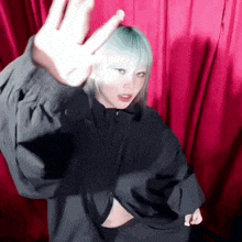 a woman with blue hair and a black jacket is making a peace sign