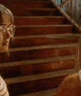 a woman in a dress is standing on a set of stairs wearing a coat .