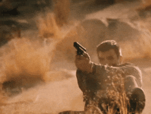 a man is holding a gun in a field of dry grass