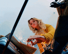 a woman in a yellow sweater holds a ring in her hand