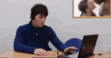 a man wearing headphones sits in front of a samsung laptop computer