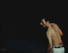 a man without a shirt is standing in the dark