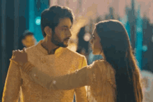 a man and a woman are standing next to each other looking at each other .