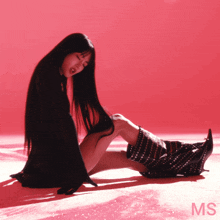 a woman with long black hair is kneeling on the floor with the letters ms behind her