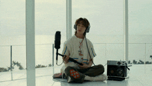 a person wearing headphones is sitting on the floor with a microphone