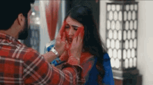 a man is covering a woman 's face with red powder .