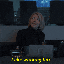 a woman sitting at a desk with the words " i like working late " on the bottom