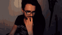 a man wearing glasses and a shirt that says heart on it bites his nails