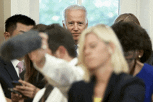 a man in a suit and tie stands in a crowd