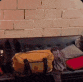 a yellow bag is sitting on a black couch in front of a brick wall .