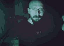 a blurry picture of a man standing in a dark room with glasses on .