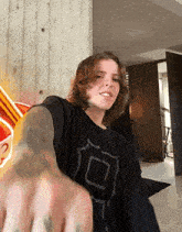 a young man with long hair and tattoos is giving a fist bump in a living room .