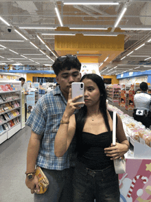a man and a woman are taking a selfie in a grocery store