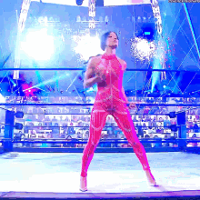 a woman in a pink bodysuit is standing in a wrestling ring with fireworks in the background