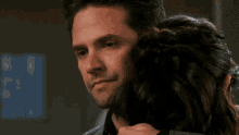a man with his eyes closed is hugging a woman