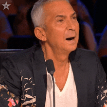 a man speaking into a microphone with a star on the bottom right