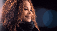 a woman with curly hair and a scarf around her neck is smiling
