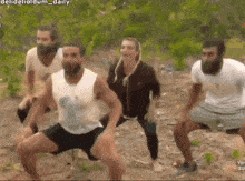 a group of people are doing squats in the dirt in a video .