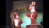 two stuffed animals are standing next to each other on a stage . one of the animals is wearing an uncle sam hat .