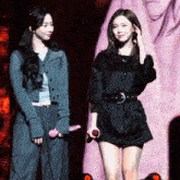 two women standing next to each other on a stage holding microphones