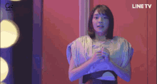 a woman is standing in front of a red door with line tv written on the bottom right