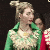 a woman wearing a green jacket and a red dress is standing next to another woman .
