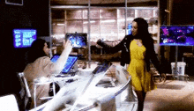 a woman in a yellow dress is standing next to a man in an office .