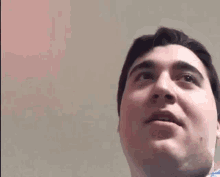 a man is looking up at the camera while wearing a blue shirt and making a funny face .