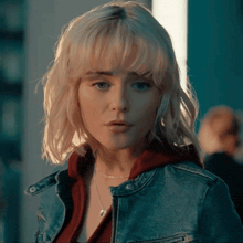a woman with blonde hair and blue eyes is wearing a denim jacket