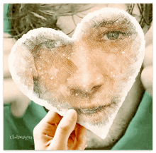 a person is holding a heart shaped piece of paper with a face on it