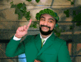 a man wearing a green suit and a green hat points up