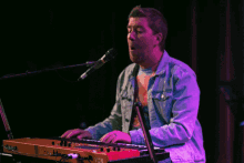 a man singing into a microphone while playing a red keyboard