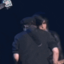 a man singing into a microphone while another man kisses his cheek