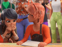 a girl with pink hair is sitting at a table with other girls