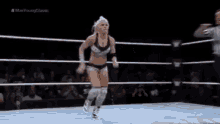 a woman in a wrestling ring with a referee behind her