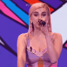 a woman is singing into a microphone while wearing a colorful top .