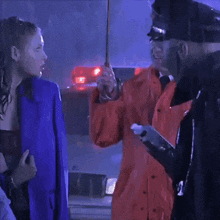 a man in an orange raincoat is talking to a woman in a blue jacket