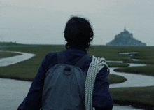 a person with a backpack and a rope around their shoulder stands in front of a body of water