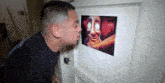 a man is looking through a peephole at a picture of a scary face .