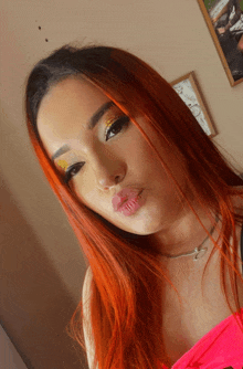 a woman with red hair is wearing a pink top and a necklace