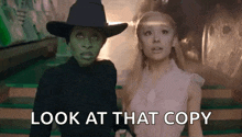 two women are standing next to each other with the words `` look at that copy '' written on the screen .