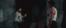 two men are fighting each other in a dark room in a movie .
