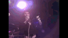 a man is singing into a microphone on a stage while wearing gloves .
